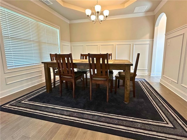 360 Walker Rd, Byron, GA 31008 - dining space with a decorative wall, a tray ceiling, a chandelier, arched walkways, and wood finished floors