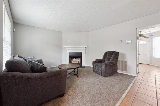 living room featuring ceiling fan, a healthy amount of sunlight, light tile patterned floors, and a textured ceiling