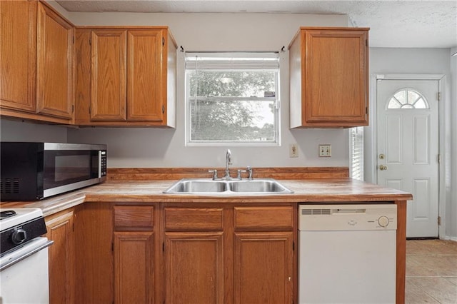 kitchen with white appliances, sink, light tile patterned floors, and plenty of natural light