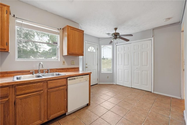 kitchen featuring plenty of natural light, sink, white dishwasher, and light tile patterned floors