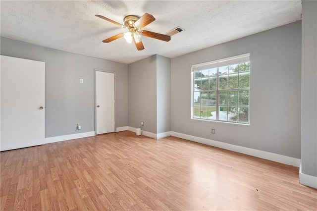 empty room featuring a textured ceiling, light wood-type flooring, and ceiling fan