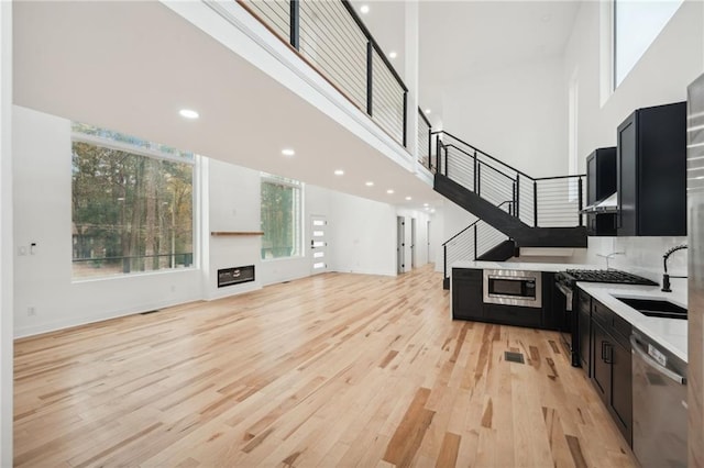 kitchen with light hardwood / wood-style floors, a high ceiling, and stainless steel fridge