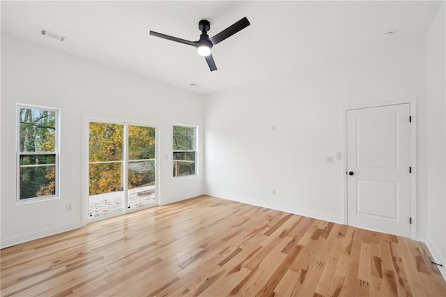 empty room featuring light wood-type flooring, a barn door, and ceiling fan