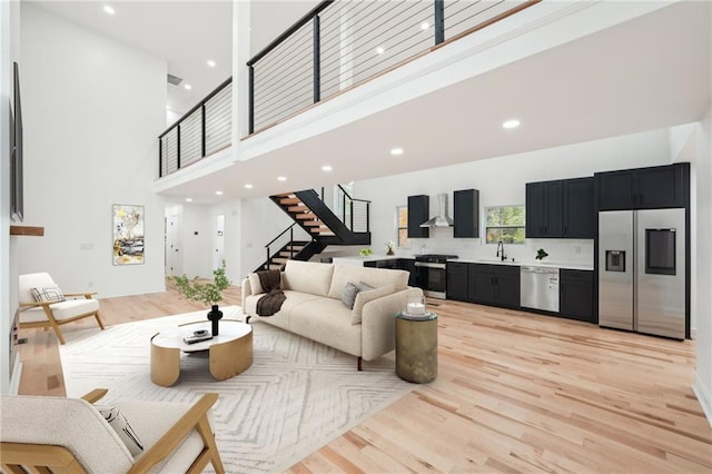 living room featuring a high ceiling, light wood-type flooring, and sink