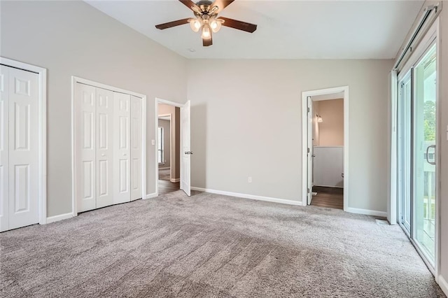 unfurnished bedroom featuring ceiling fan, two closets, vaulted ceiling, and multiple windows