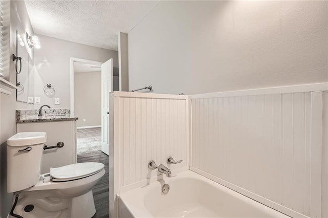 bathroom with a textured ceiling, vanity, and toilet