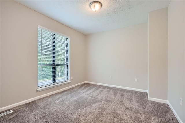 carpeted empty room featuring a textured ceiling