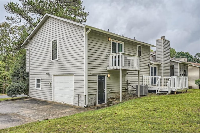 rear view of property featuring a lawn, a garage, and a wooden deck