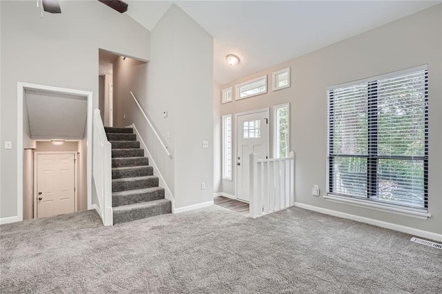 carpeted foyer with ceiling fan and vaulted ceiling