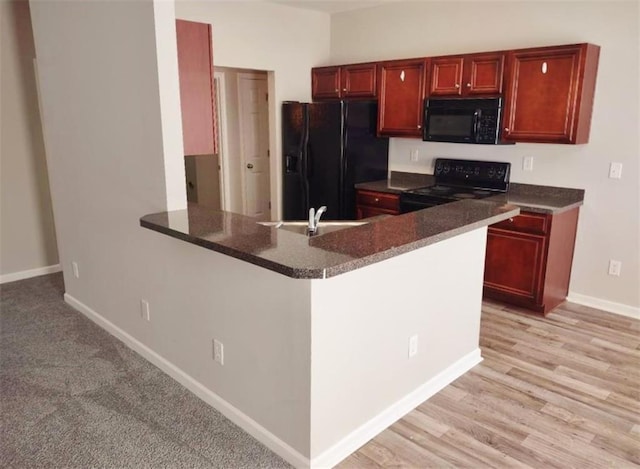 kitchen with black appliances, sink, and light wood-type flooring