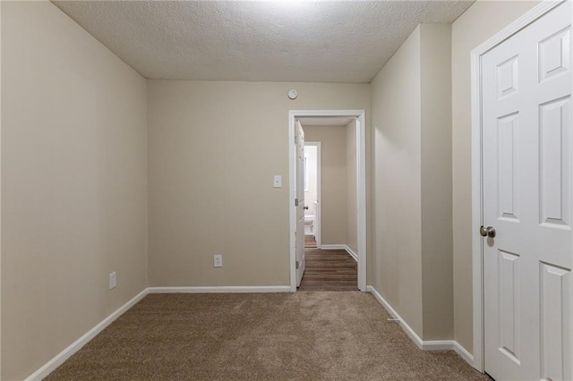 carpeted empty room featuring a textured ceiling