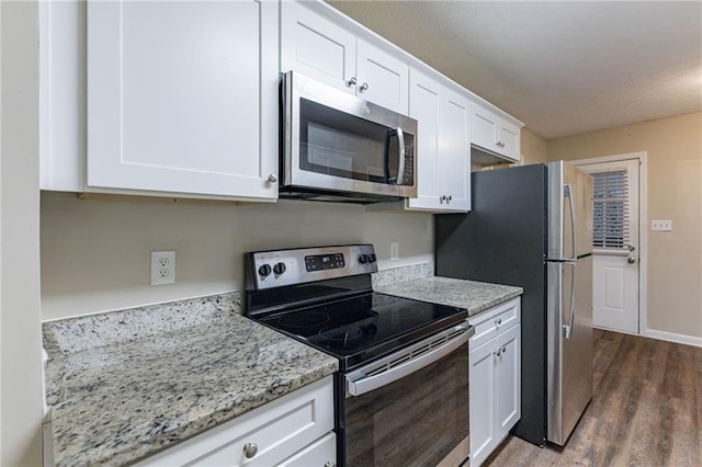 kitchen with light stone countertops, white cabinetry, stainless steel appliances, and dark hardwood / wood-style floors