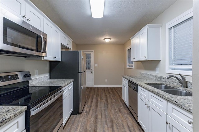 kitchen featuring white cabinets, sink, dark hardwood / wood-style floors, light stone counters, and stainless steel appliances