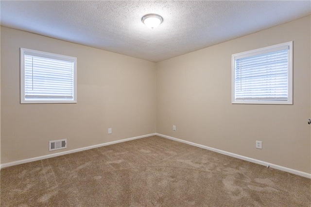 carpeted spare room featuring a textured ceiling