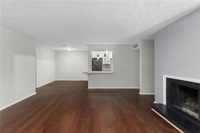 603 Summit N Dr NE Unit 603, Atlanta, GA 30324 - unfurnished living room with a fireplace with raised hearth, dark wood-style flooring, baseboards, and a textured ceiling