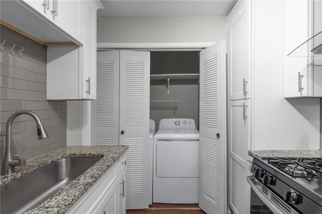 603 Summit N Dr NE Unit 603, Atlanta, GA 30324 - kitchen featuring washer / dryer, a sink, white cabinets, tasteful backsplash, and gas stove