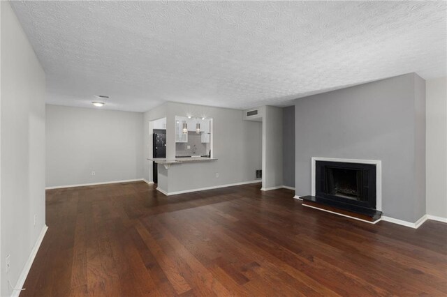 603 Summit N Dr NE Unit 603, Atlanta, GA 30324 - unfurnished living room with dark wood-type flooring, baseboards, a textured ceiling, and a fireplace with raised hearth