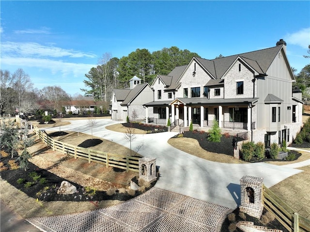 view of front of property featuring board and batten siding, driveway, and fence