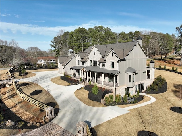 exterior space featuring covered porch, a chimney, and curved driveway