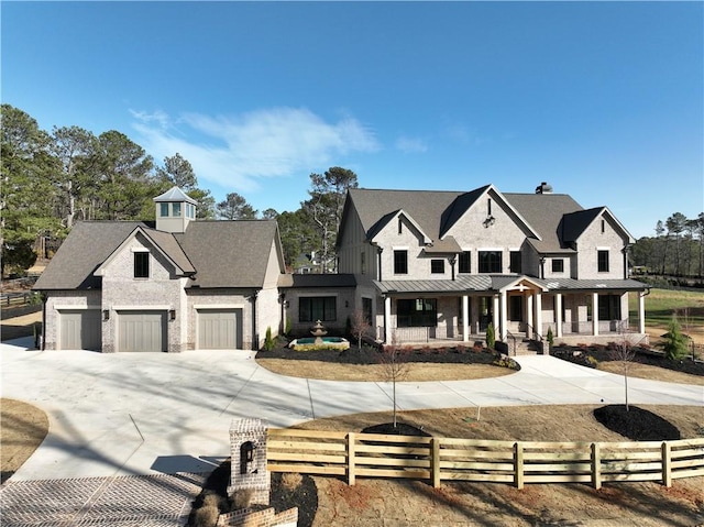 modern inspired farmhouse with a fenced front yard, covered porch, a standing seam roof, metal roof, and driveway