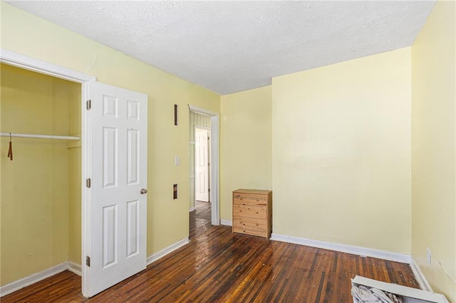 unfurnished bedroom with a textured ceiling, a closet, and dark hardwood / wood-style flooring