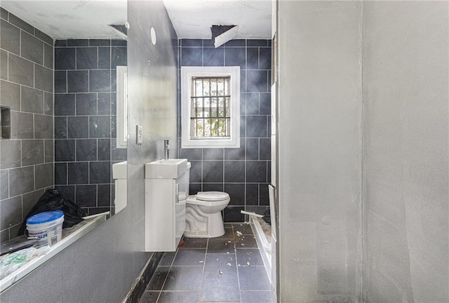 bathroom featuring toilet, walk in shower, sink, and tile walls