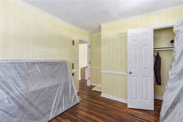 bedroom with dark wood-type flooring, a textured ceiling, crown molding, and a closet