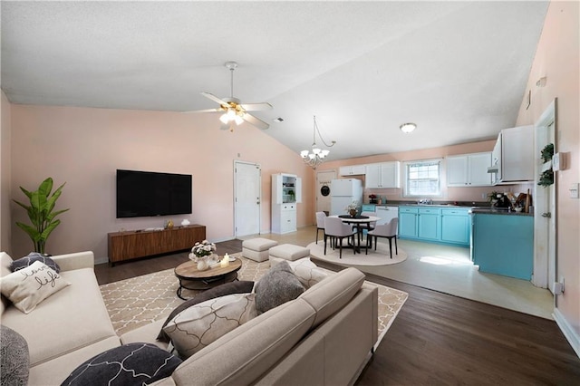 living room with dark hardwood / wood-style flooring, ceiling fan with notable chandelier, vaulted ceiling, and sink