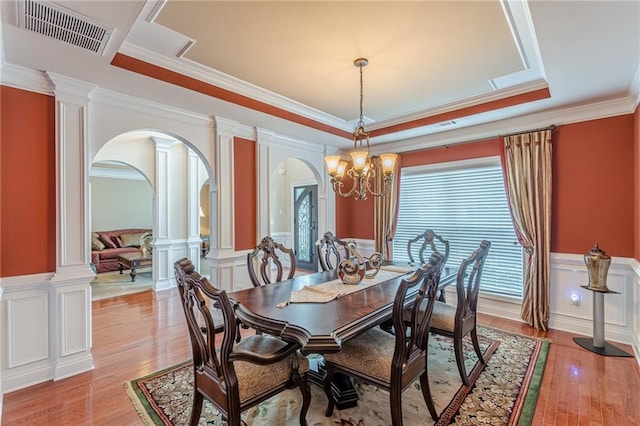 3202 Lucky Pl, Conyers, GA 30013 - dining area featuring arched walkways, a decorative wall, ornamental molding, wainscoting, and light wood-style floors