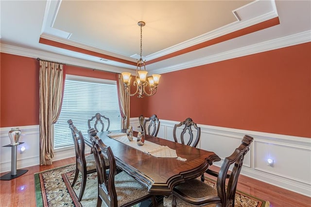 3202 Lucky Pl, Conyers, GA 30013 - dining area featuring a raised ceiling, ornamental molding, wood finished floors, wainscoting, and a chandelier