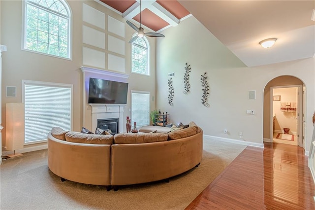 3202 Lucky Pl, Conyers, GA 30013 - carpeted living room featuring a high ceiling, arched walkways, a glass covered fireplace, ceiling fan, and wood finished floors