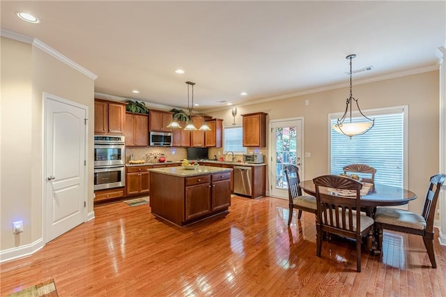 3202 Lucky Pl, Conyers, GA 30013 - kitchen featuring appliances with stainless steel finishes, brown cabinetry, a center island, light wood finished floors, and crown molding