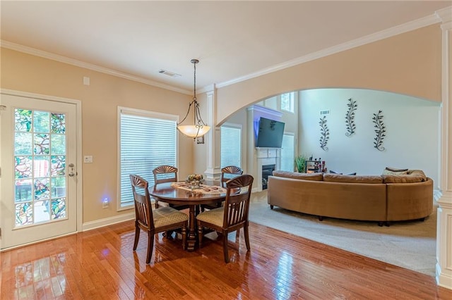3202 Lucky Pl, Conyers, GA 30013 - dining area with light wood-style flooring, plenty of natural light, a glass covered fireplace, crown molding, and arched walkways