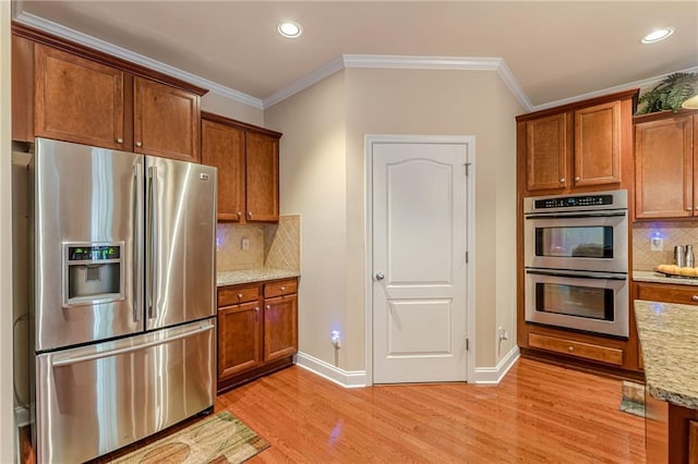 3202 Lucky Pl, Conyers, GA 30013 - kitchen featuring appliances with stainless steel finishes, light wood-style flooring, brown cabinets, recessed lighting, and crown molding