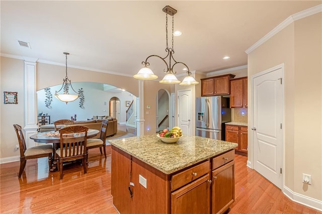 3202 Lucky Pl, Conyers, GA 30013 - kitchen with stainless steel fridge with ice dispenser, arched walkways, brown cabinetry, a kitchen island, and pendant lighting