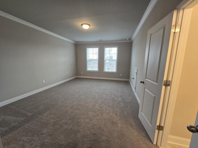 unfurnished bedroom with crown molding, a walk in closet, a closet, and dark colored carpet