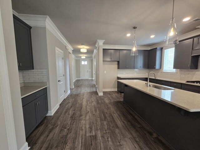 kitchen featuring sink, appliances with stainless steel finishes, backsplash, a center island with sink, and dark hardwood / wood-style flooring