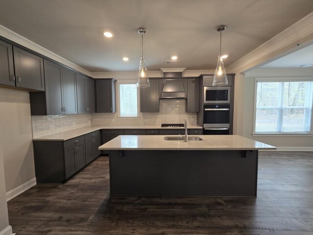 kitchen featuring appliances with stainless steel finishes, pendant lighting, sink, ornamental molding, and wall chimney range hood