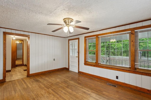 spare room with hardwood / wood-style flooring, baseboards, a ceiling fan, ornamental molding, and a textured ceiling