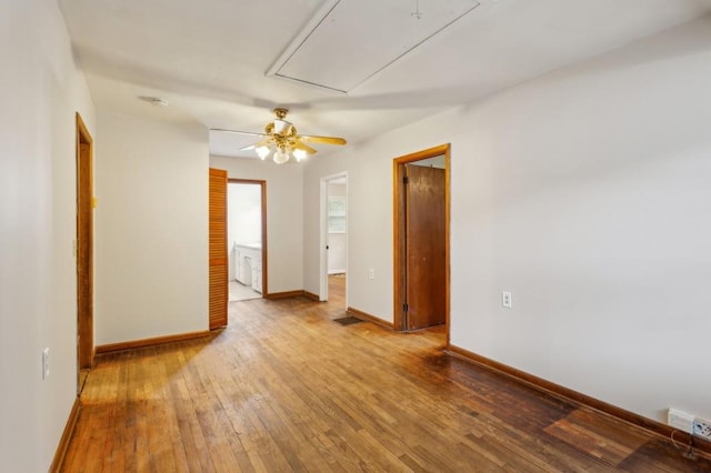 empty room with attic access, hardwood / wood-style flooring, baseboards, and ceiling fan