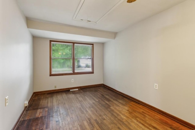 empty room featuring hardwood / wood-style flooring, attic access, and baseboards