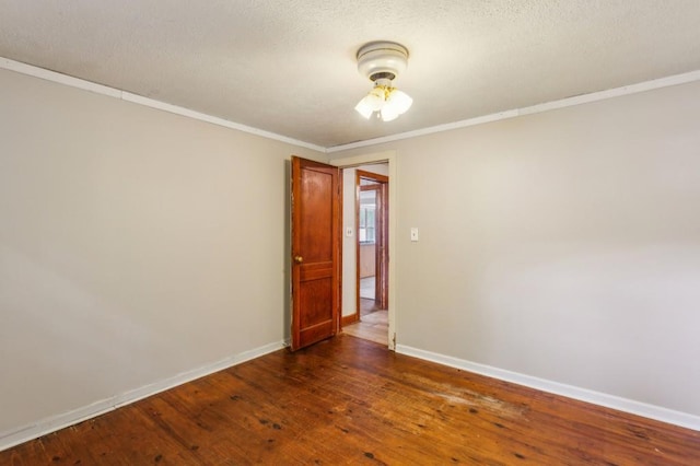 empty room featuring baseboards, dark wood-style flooring, ornamental molding, and a textured ceiling