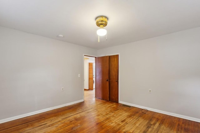 empty room with baseboards, wood finished floors, and a smoke detector