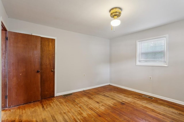 unfurnished bedroom with wood-type flooring, baseboards, and a closet