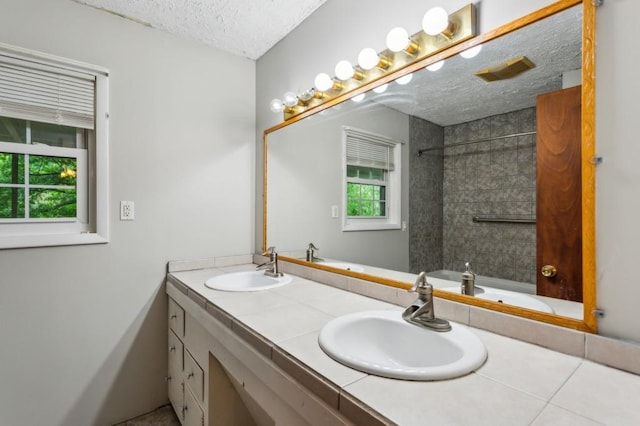 bathroom with a textured ceiling and double vanity