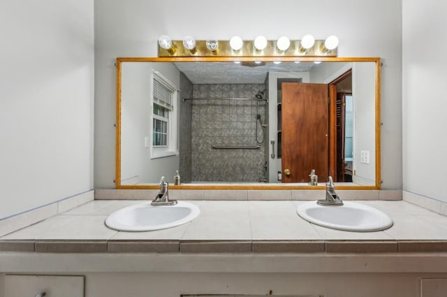 bathroom featuring double vanity and a tile shower