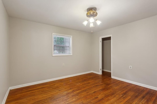 spare room featuring baseboards, wood finished floors, and a ceiling fan