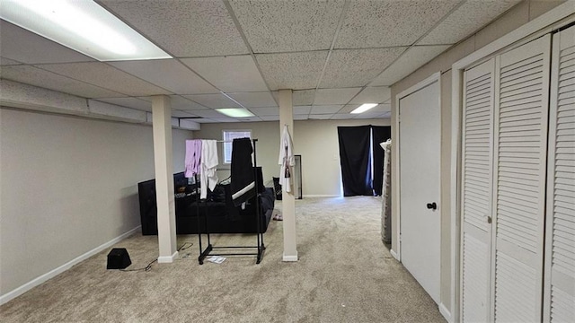 finished below grade area with baseboards, a drop ceiling, and carpet flooring