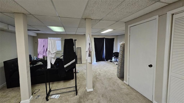 below grade area featuring a drop ceiling, carpet flooring, and baseboards