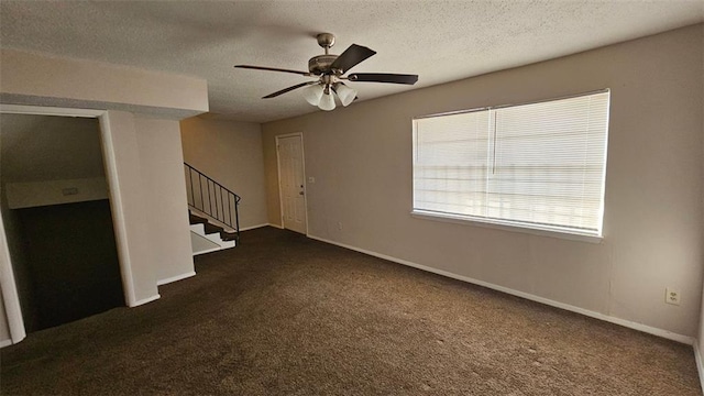 unfurnished living room with dark colored carpet, baseboards, stairway, and a textured ceiling